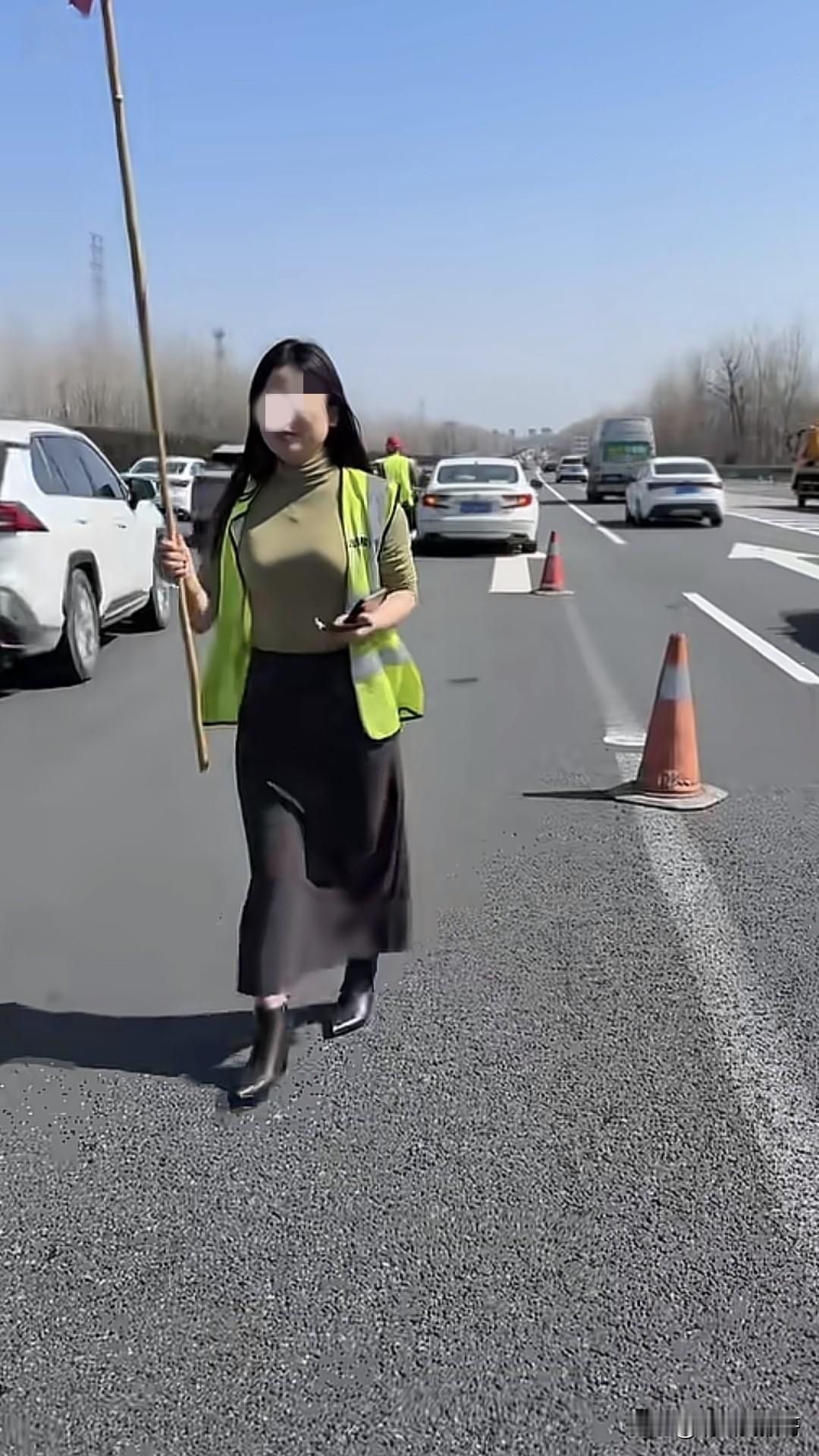 一网友发视频说路上偶遇一个女司机的车抛锚了，她身穿反光马甲，车后放着反光锥，举着