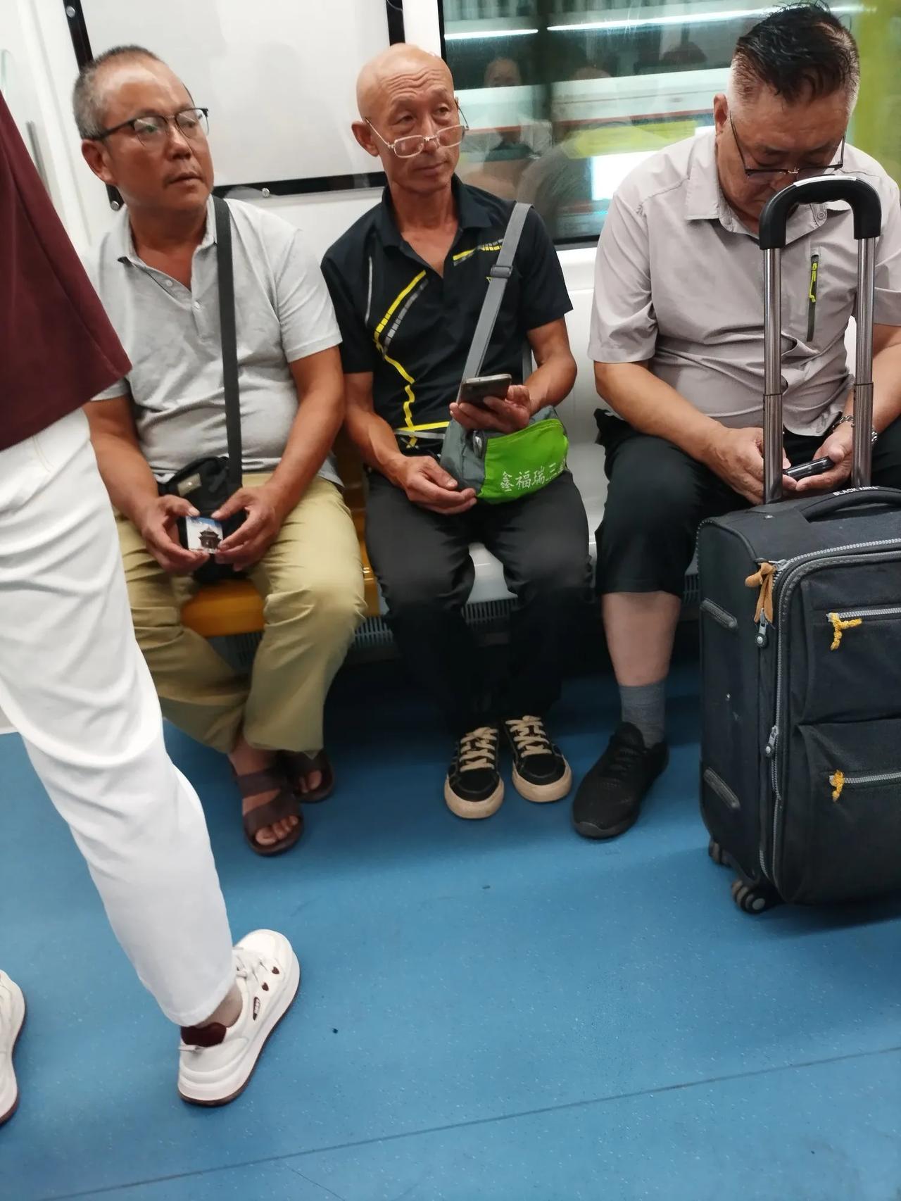 地铁对面坐着三位戴眼镜的老者。

中间这位就是一个企业退休的工人，退休金在400