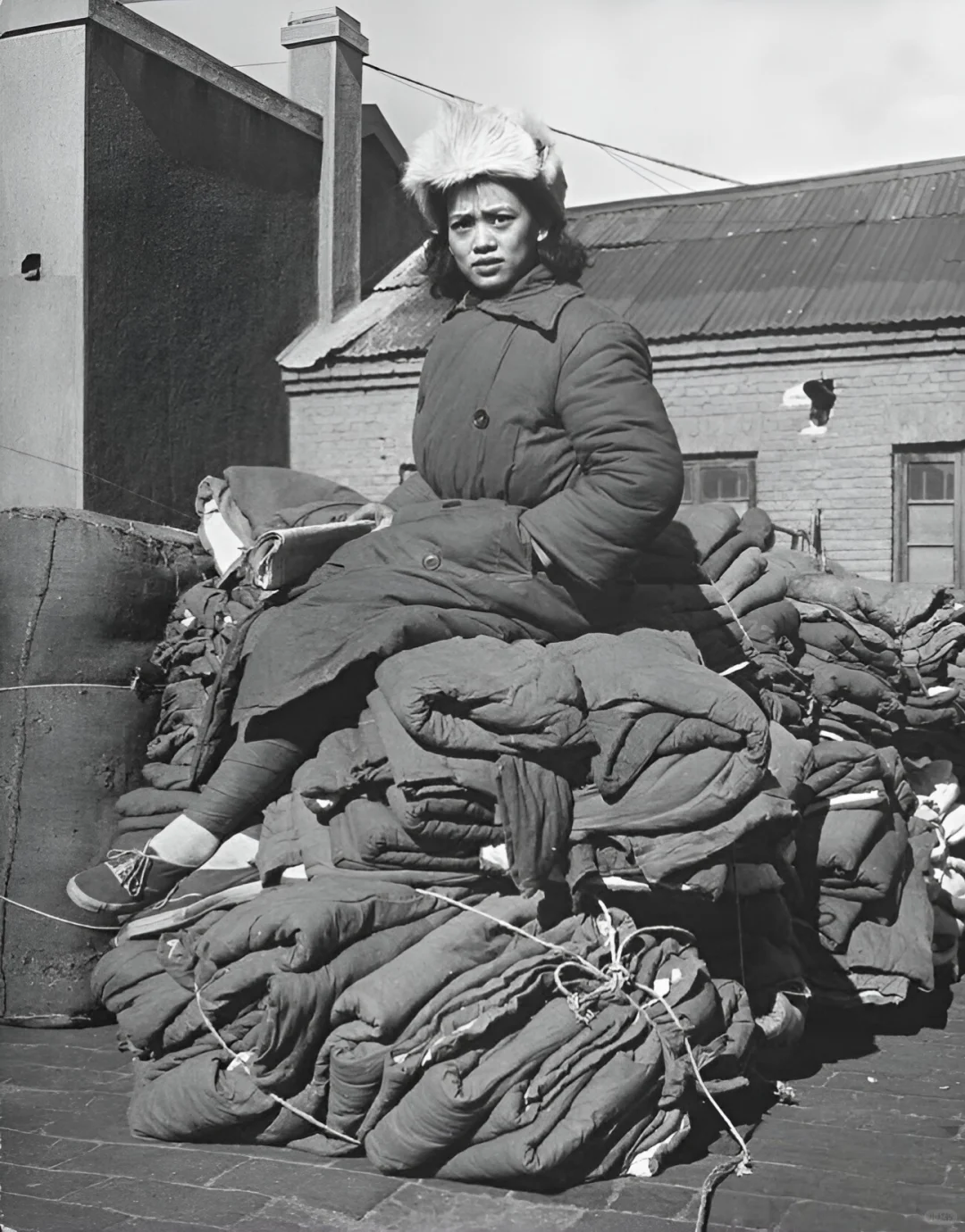 淮海战役期间，一位国民党女兵坐在成堆的棉服上。 拍摄者是美国《生活》...