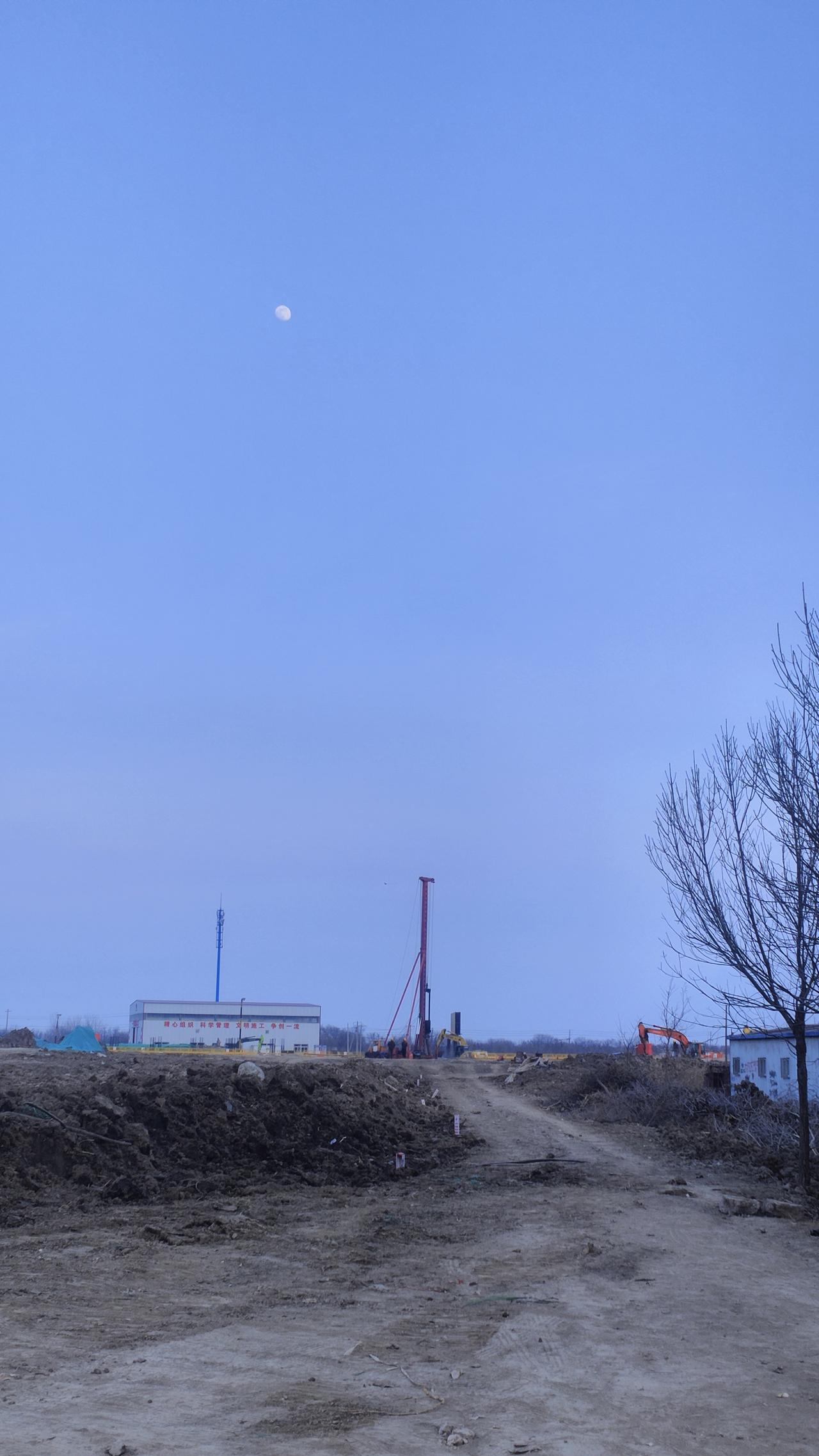 这工地可真有意思，天刚擦黑，月亮都挂上蓝汪汪的天了，机器还在“嗡嗡”转着。
 