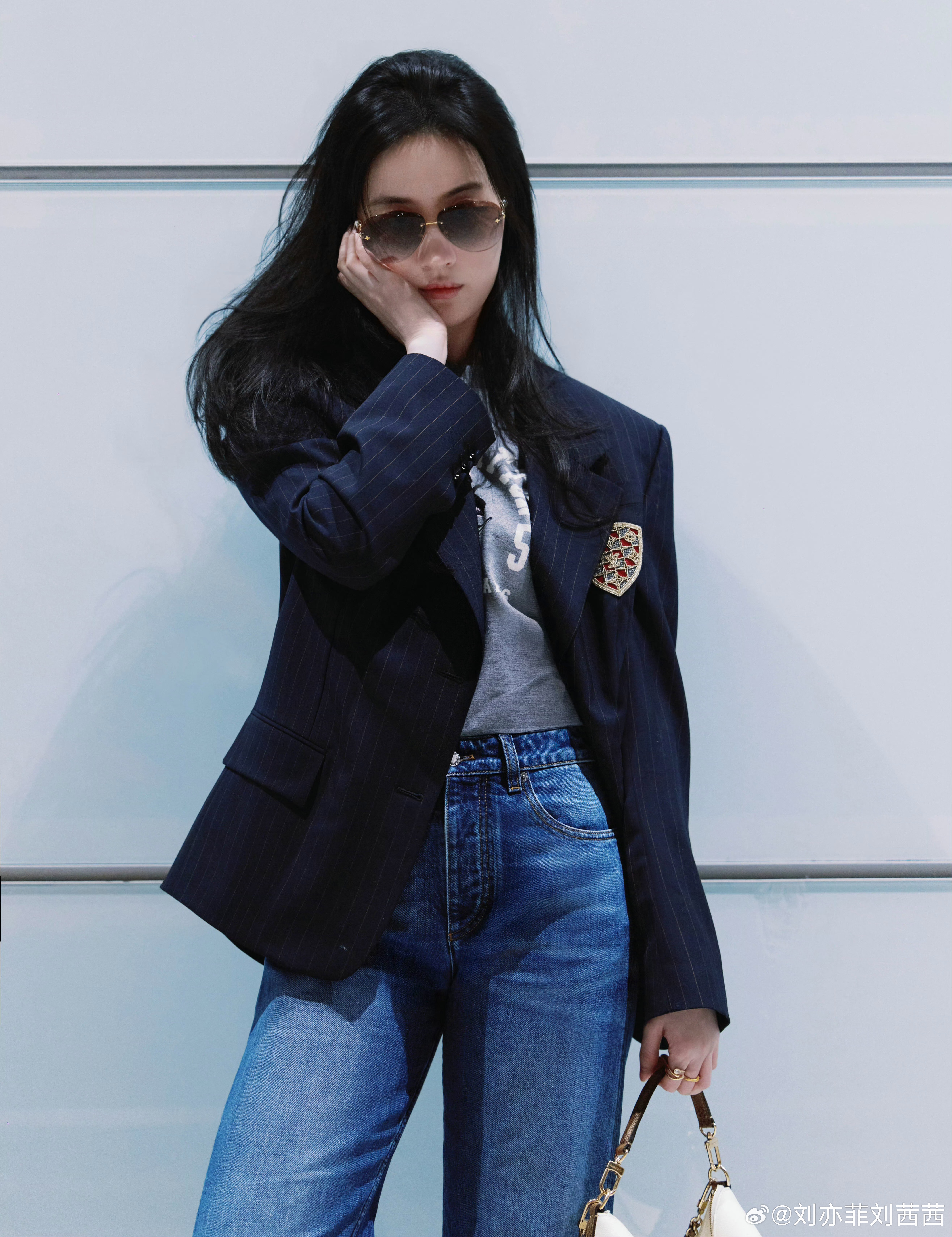 刘亦菲这次机场穿搭，上装选择了藏青色细条纹西装外套，精致徽章装饰让整体更显独特，