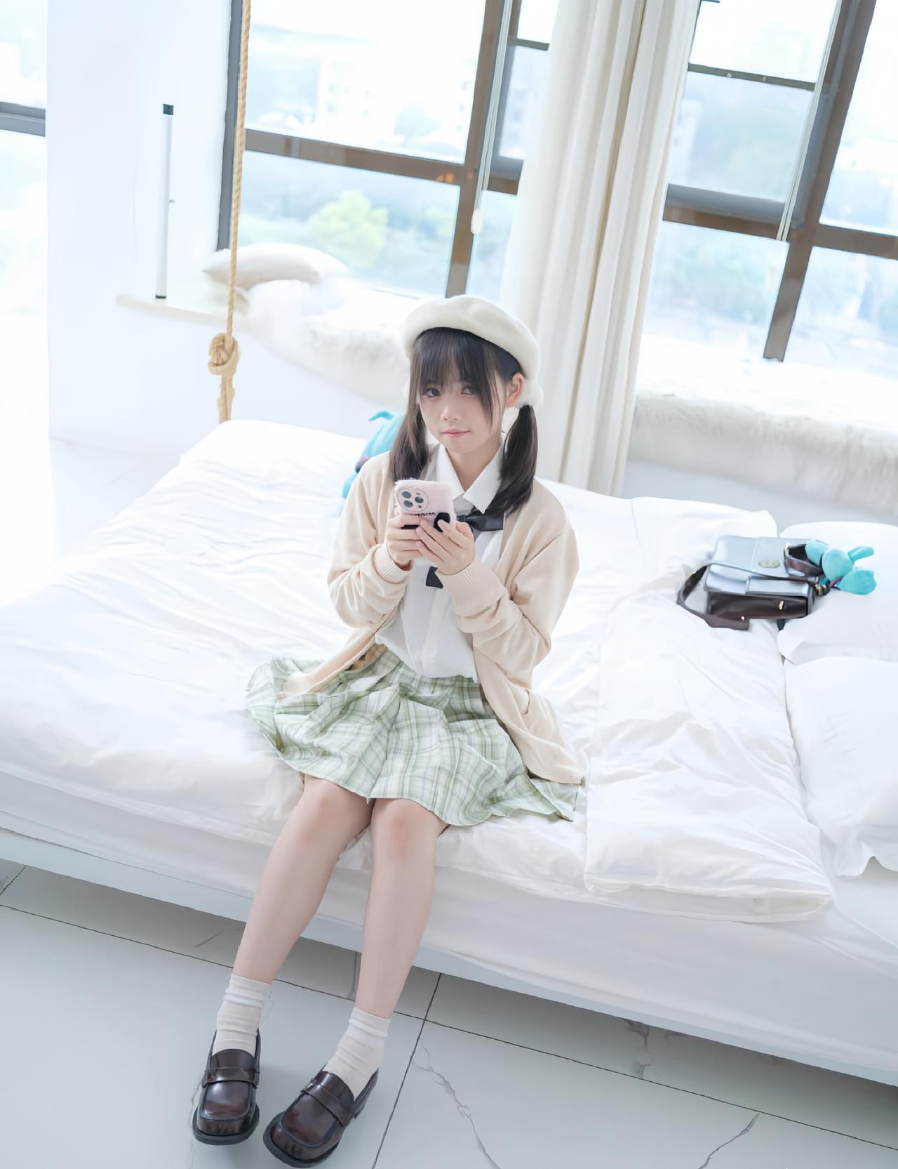 女孩在床上玩手机，穿着可爱。
美少女