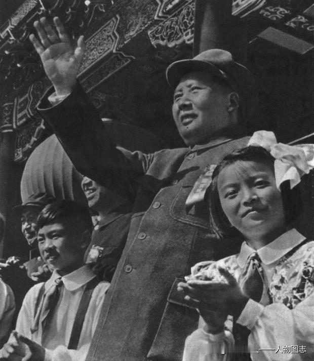 1952年国庆节，毛主席在天安门检阅台上向群众游行队伍举手答礼