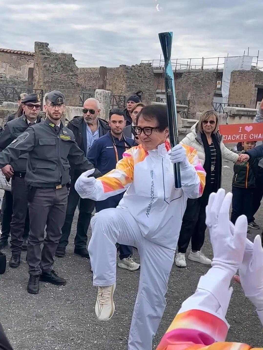 71岁的成龙在庞贝古城传递冬奥火炬，怀抱熊猫玩偶即兴上演醉拳，东西方文化在奥运圣