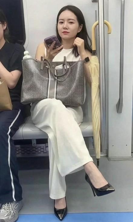 美女在民间，地铁上也不缺美女哈。

她一个手提包，一把长勾伞，穿着普通且不失大气