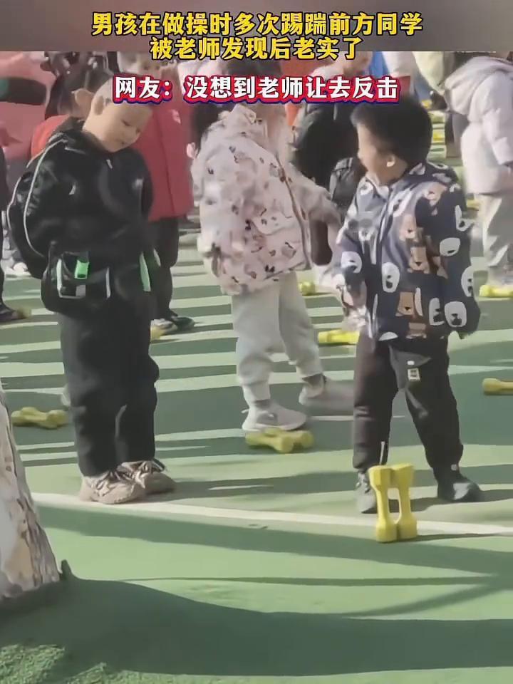 男孩在做操时多次踢踹前方同学，被老师发现后老实了。
网友：没想到老师让去反击。