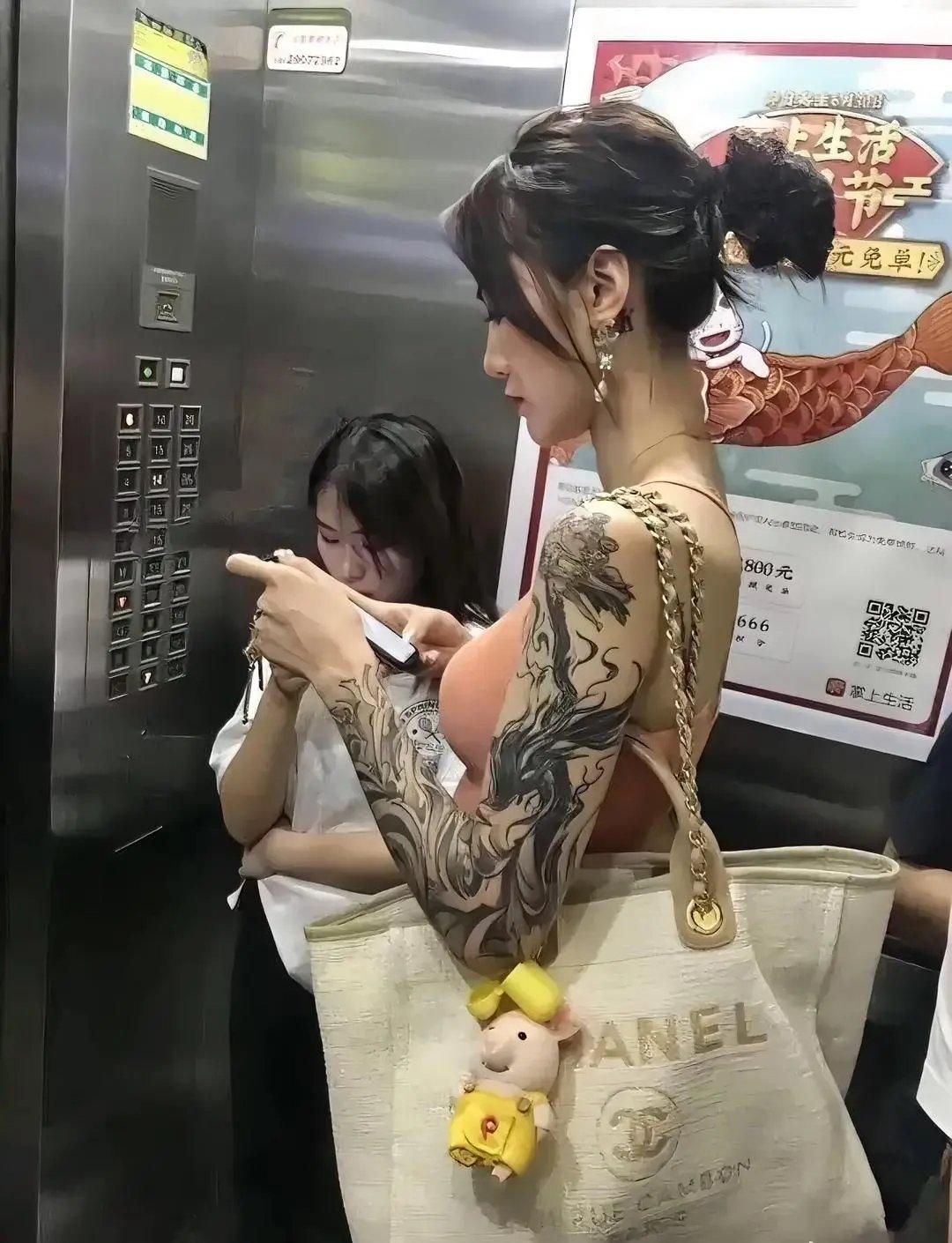 电梯里，这位身材高挑的女子，挎个布袋，长发盘起，打扮入时。

即使低头刷着手机，
