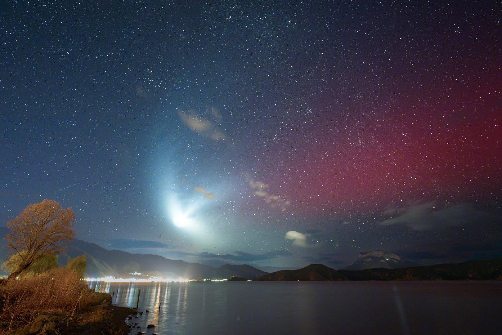 夜空被一道光劈成两半：左边是深蓝的星海，右边染上了紫红的晕彩，而那团正在高空散开