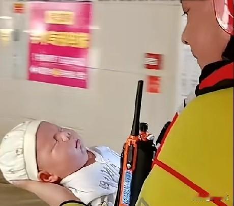 7月9日，贵港市红房子妇产医院，消防员抱着一名刚出生的婴儿转移。脚下的洪水没过膝