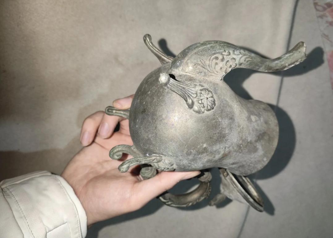 带我妈去古镇旅游，街边一家古董店，老板摆出这么个金属壶，翻过来底足、兽嘴、雕花把