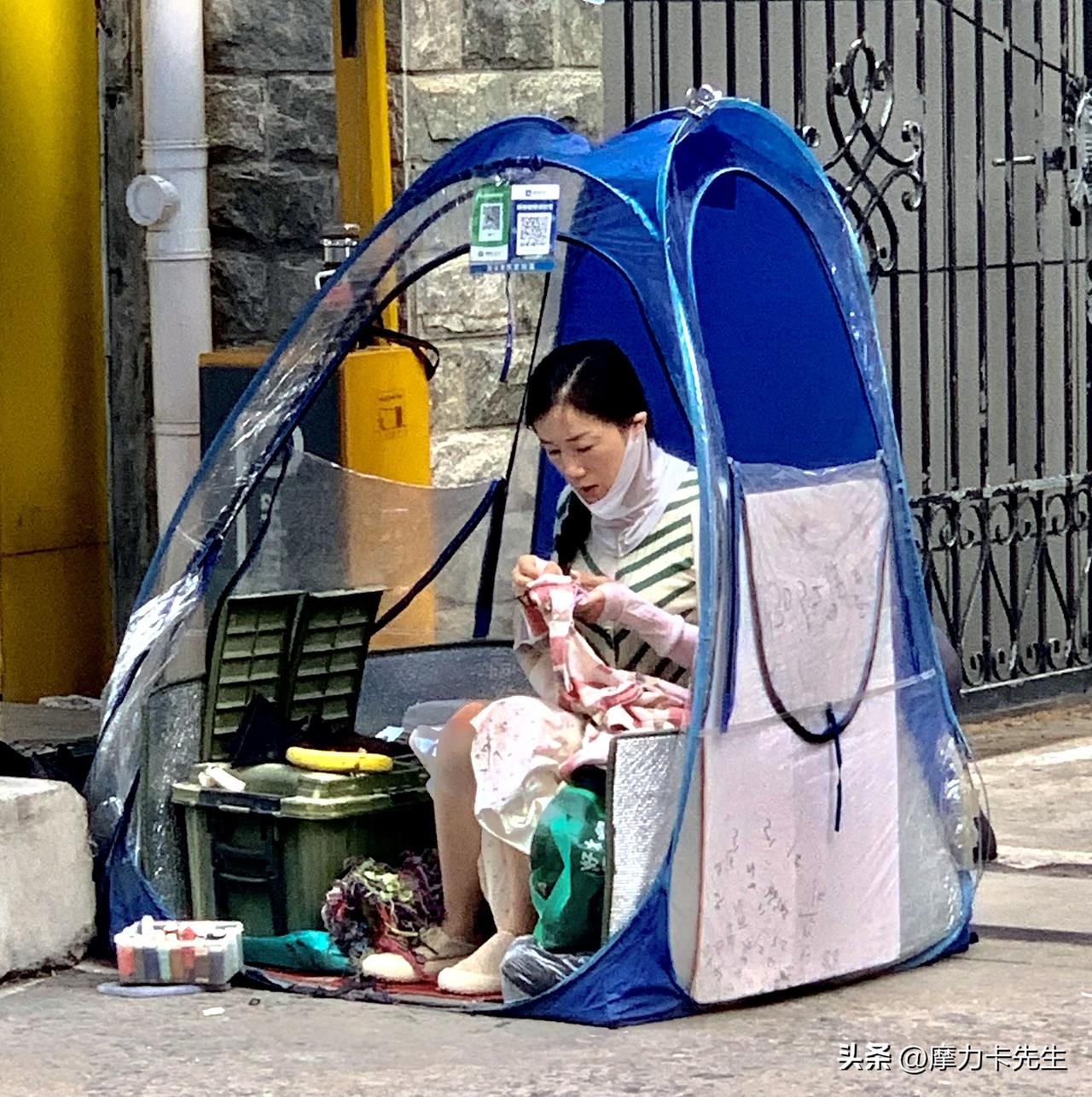 一方小小的透明帐篷，撑起街头谋生的一方小天地。指尖捻着针线细细穿梭，在人来人往的