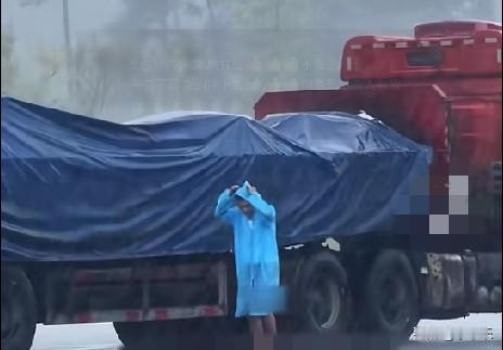 近日，重庆黎香湖服务区内突降暴雨，一货车司机独自在铺雨布，当过兵的吉林小伙李宗兴