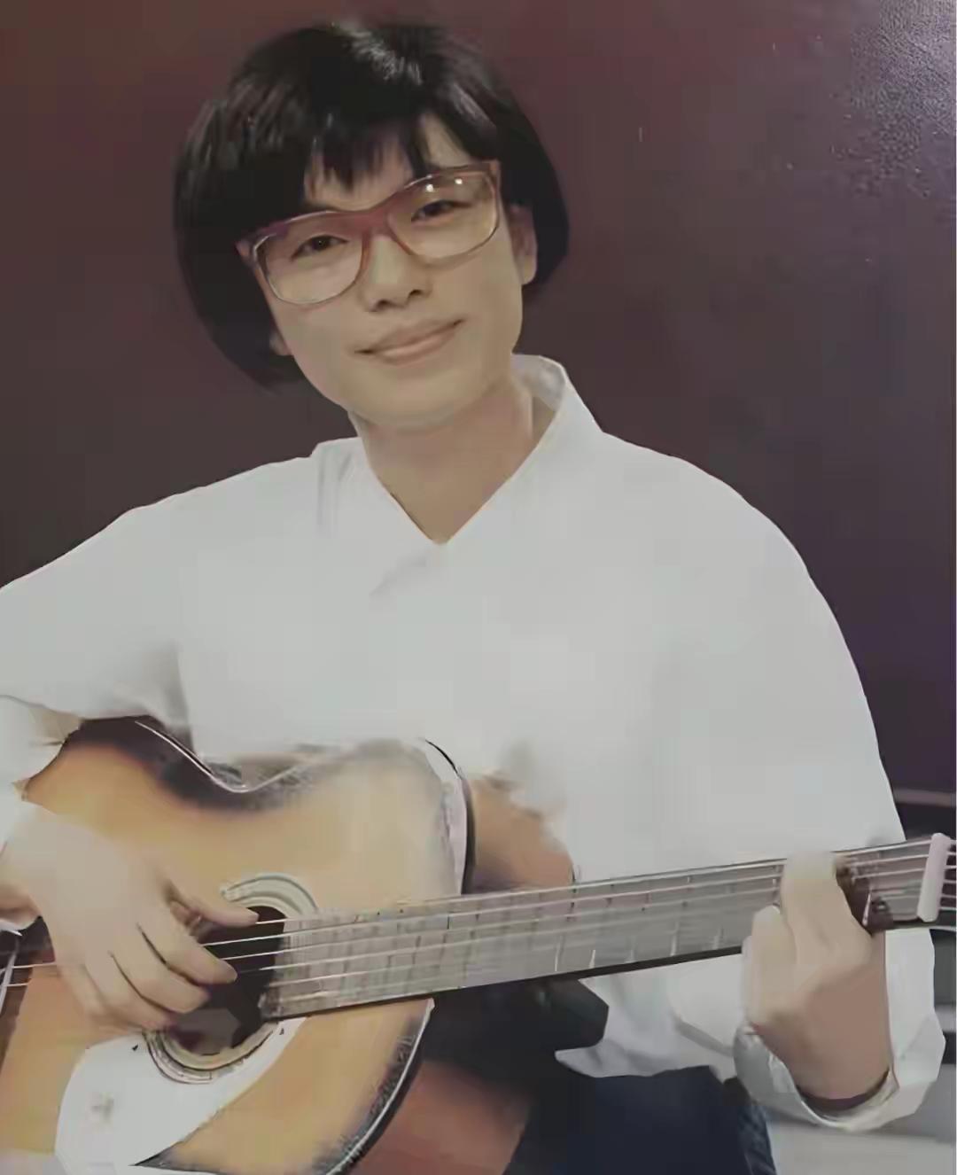 一个戴眼镜的人弹着吉他。台湾的一名女歌手。很少有人见过她的青春照，仔细看看她是谁