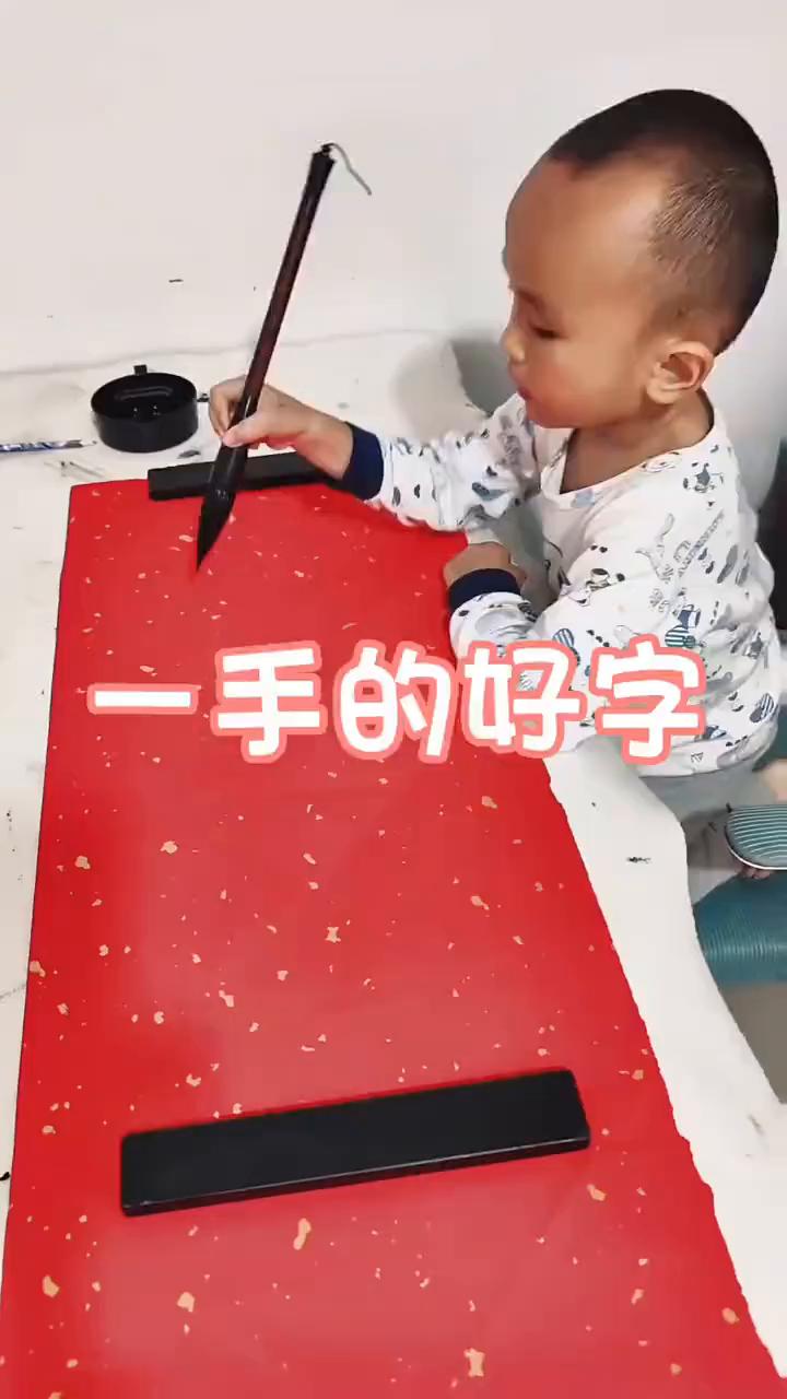 一手的好字。
这多多少少是有些天赋的。注意看眼前这一幕，萌娃拿着毛笔在纸上写生命