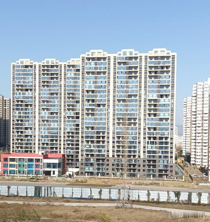 冬日暖阳泼洒金辉，塔吊长臂在蓝天下划出有力弧线。脚手架攀着新楼生长，工友的笑语混