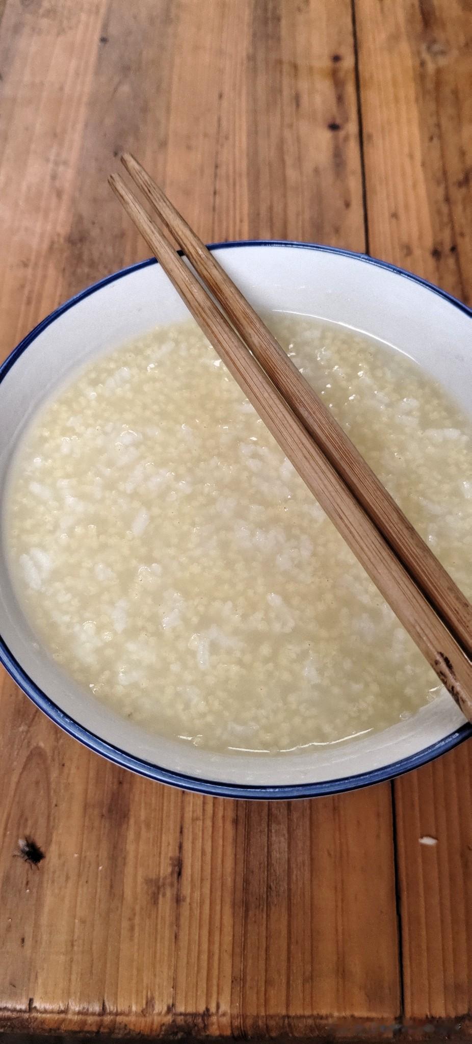 早上简单给自己熬了一碗大米混小米的粥，盛在家里老式蓝边瓷碗里，筷子随意搭在碗上。