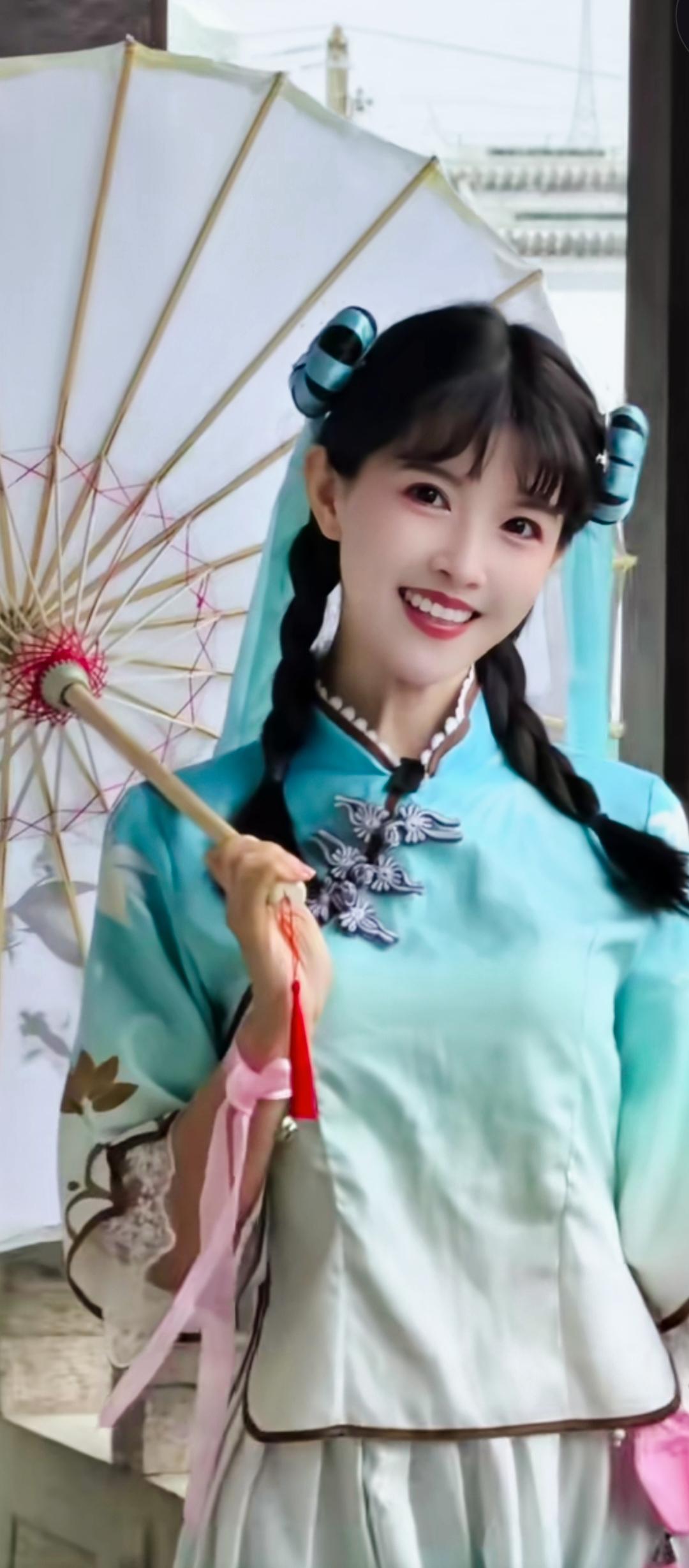 青衣美人撑伞立，笑语盈盈似画来。