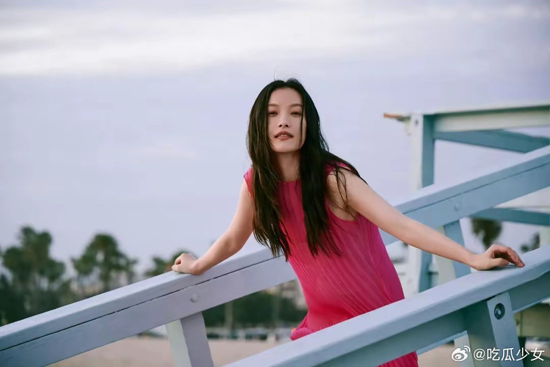 #倪妮海边玫红裙#倪妮海边写真图，玫红色无袖长裙搭配大波浪卷发，大气又美艳！ ​