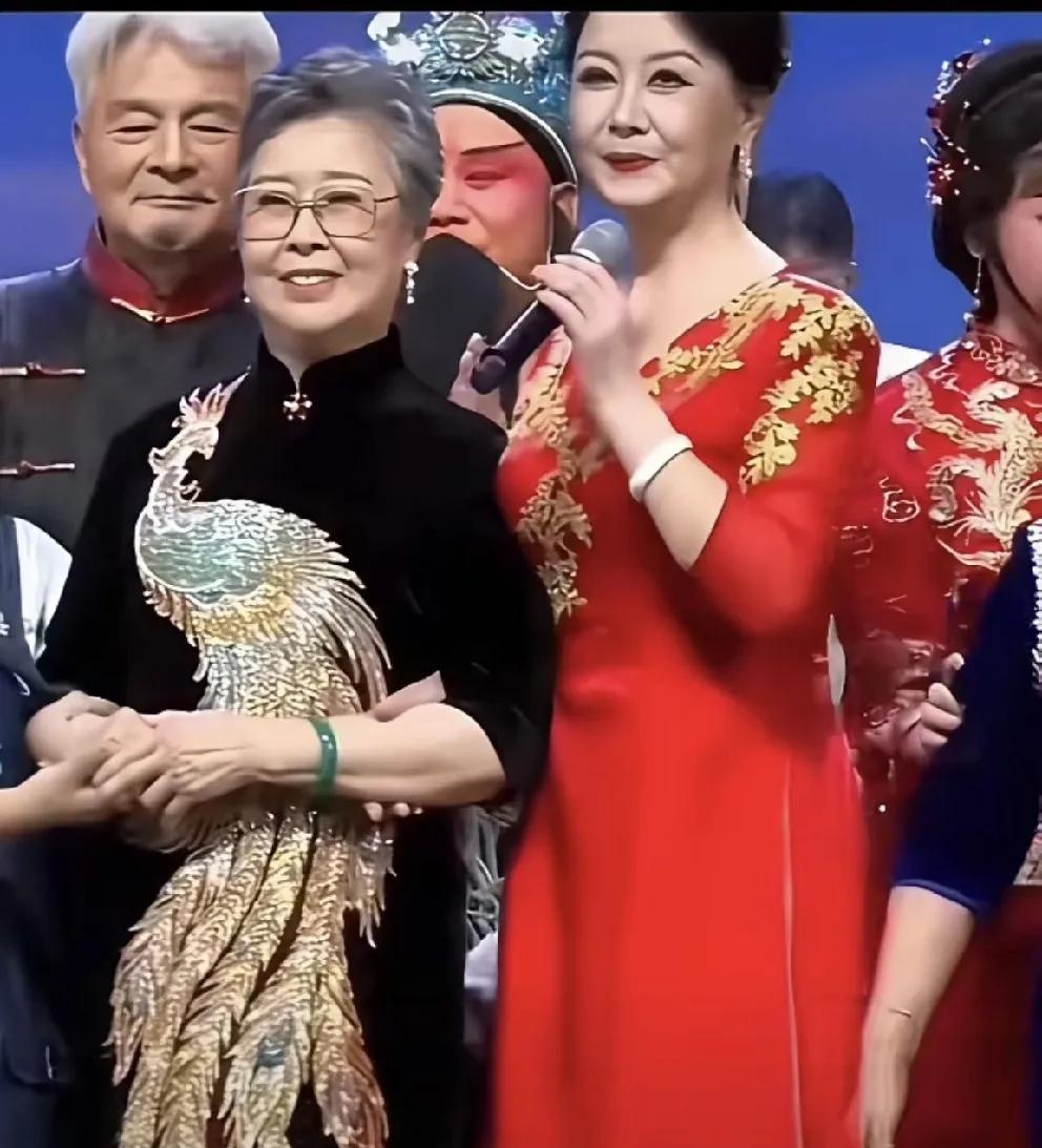 这位老人身着一款绣有凤凰图案的丝绒旗袍，真是别具一格，尽显气质与韵味。只是不知这