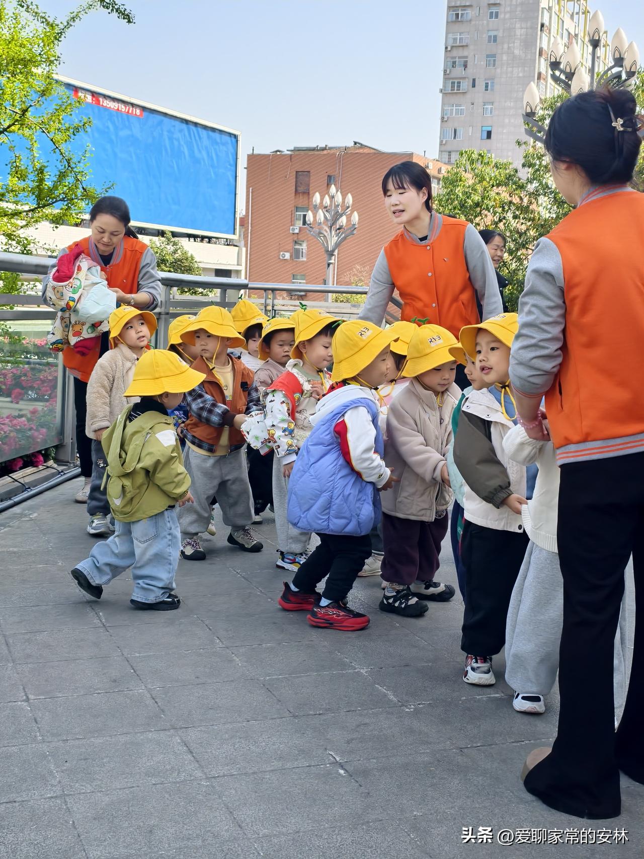 路遇一群幼儿园的小朋友，在老师的带领下在天桥上做操。他们头上都带着小黄帽，大概是