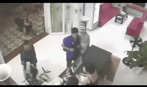 两个人在前台办理手续，一个背包男子不小心碰到了身后的一个大花瓶，男子转身想扶住花