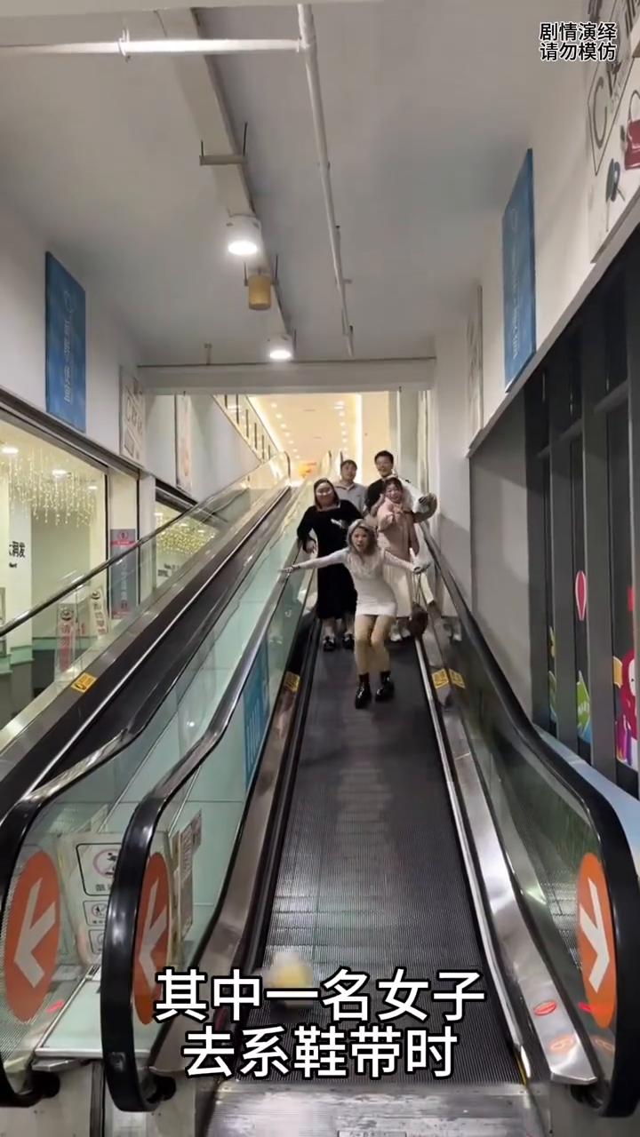 女子下电梯系鞋带时手里柚子掉下来了。
一群人正在下电梯，就当她们正在下的时候，其