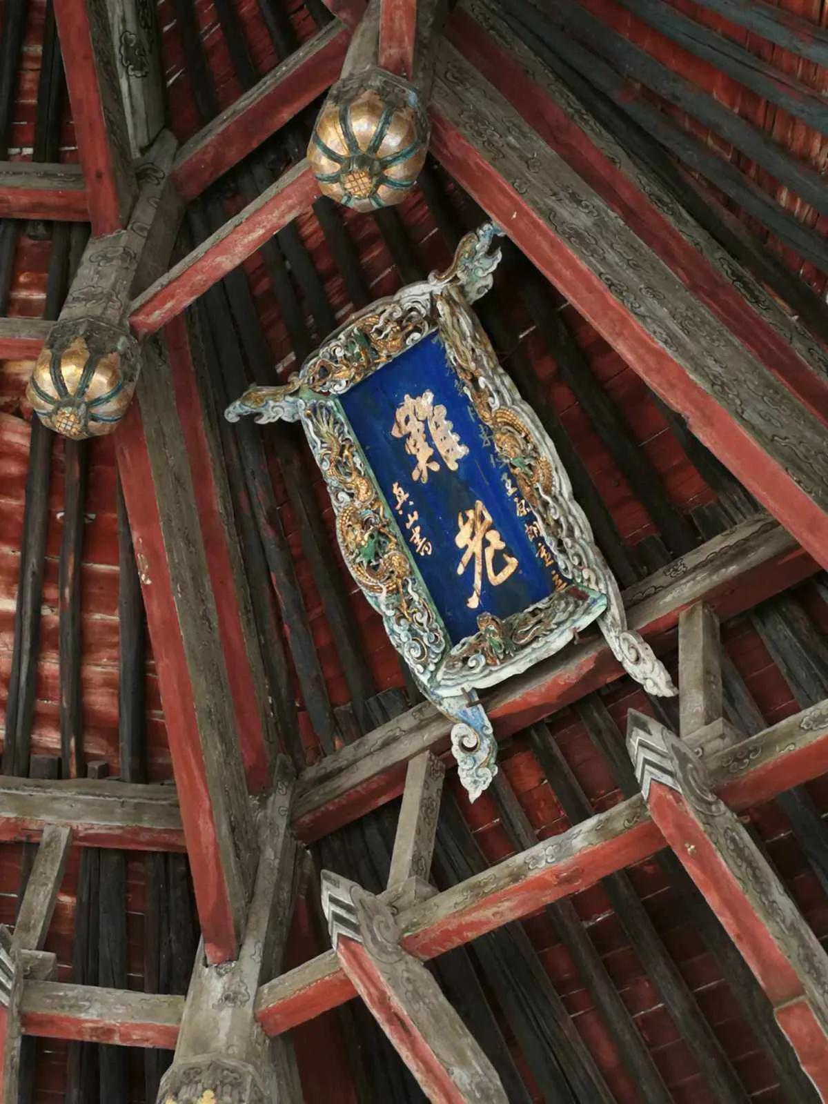 这个牌匾上的书法是什么意思？这个匾额做工非常考究，花纹箱边，蓝底黄字，应该是非常
