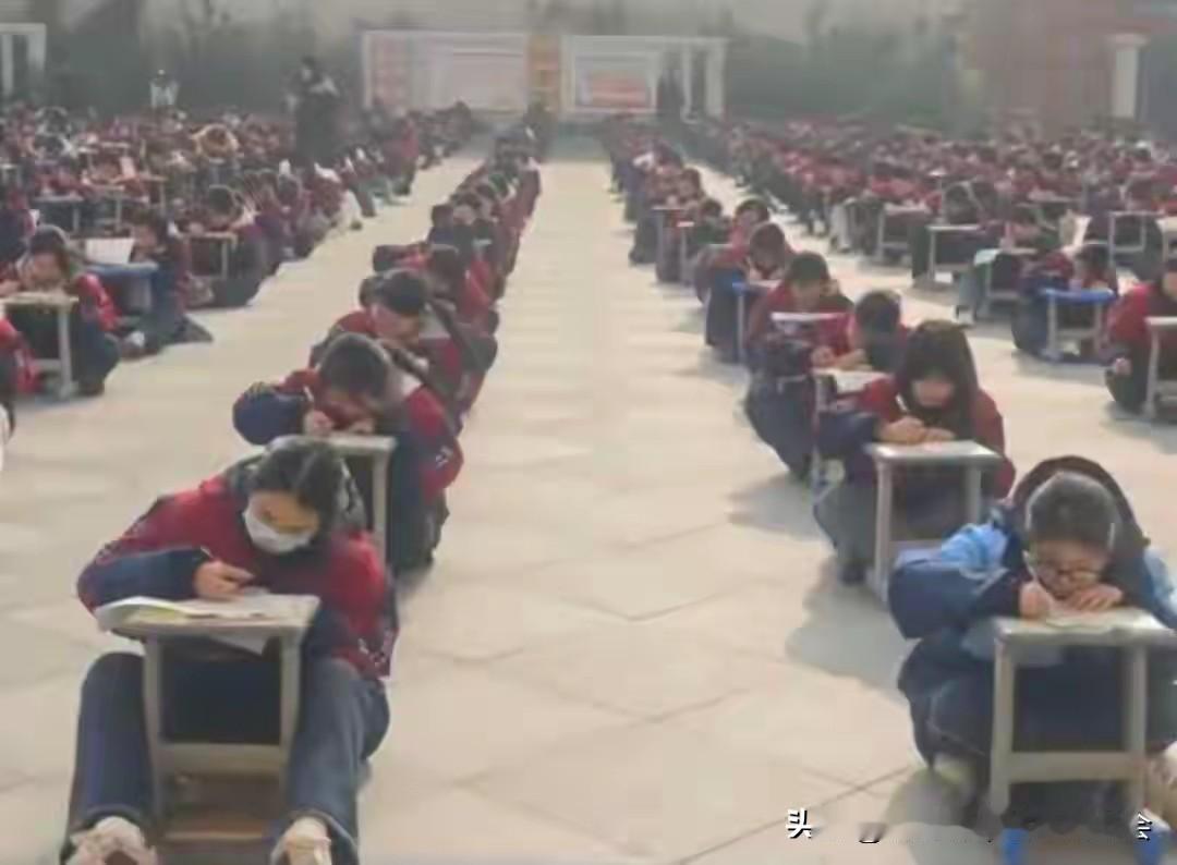 学校是一点创新都不敢啊！！近日，河南周口一高中组织数百名学生在操场趴凳考试的视频