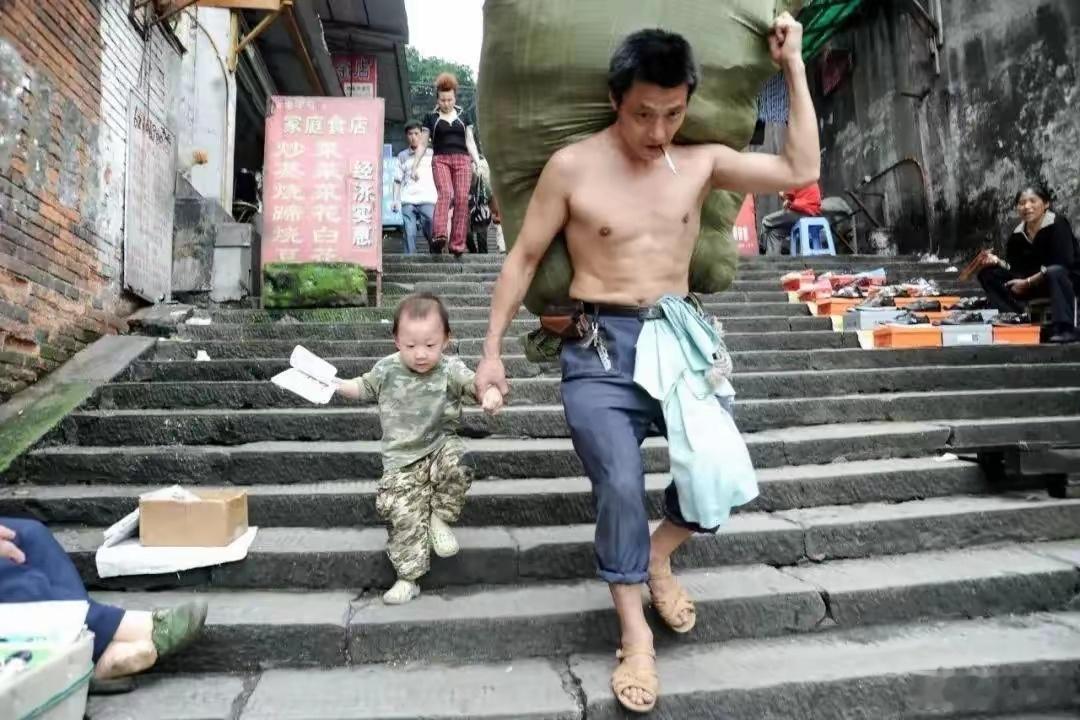 致2025年高考生2010年一张“重庆棒棒”冉光辉肩扛货物手牵幼子的照片火遍全网