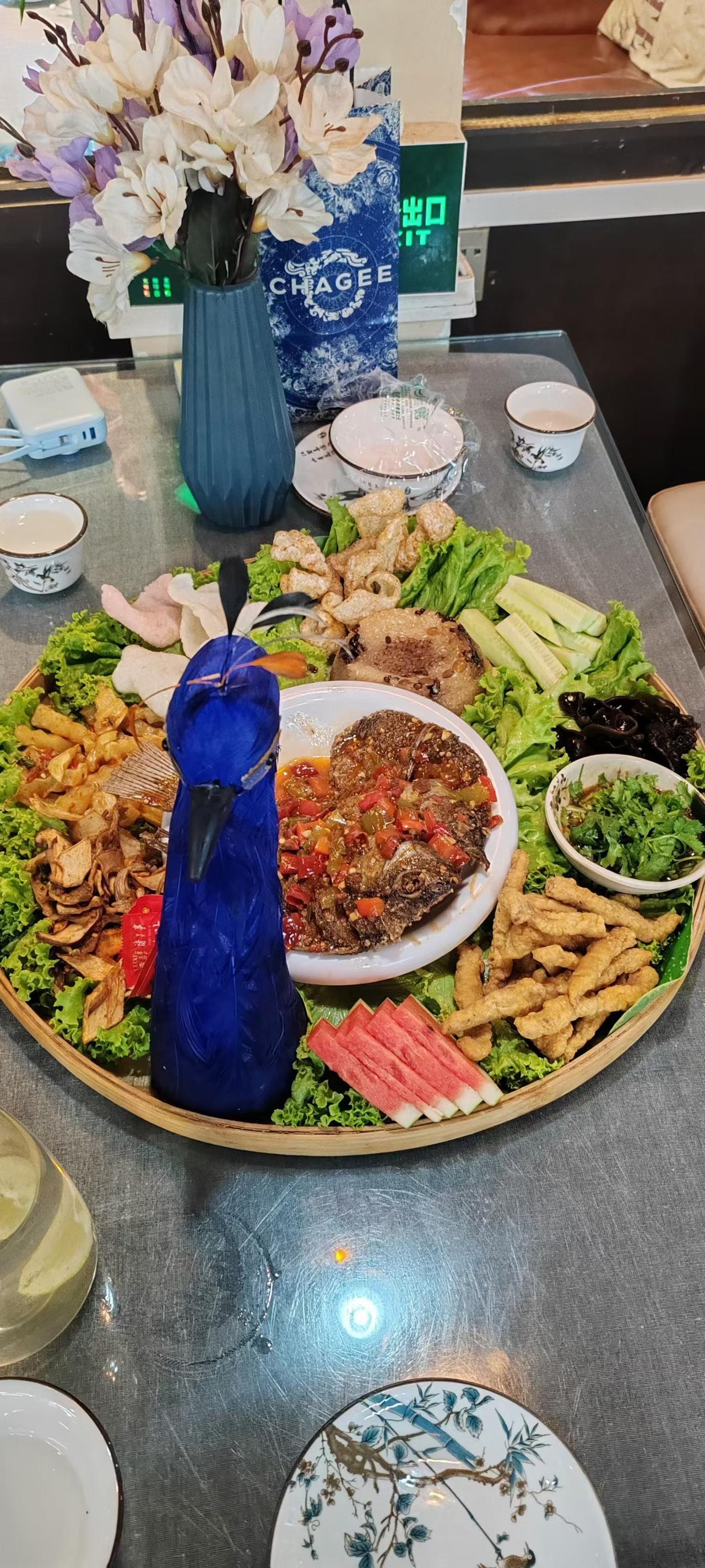 一席颇具云南风情的孔雀宴，将烟火与雅致融为一体。竹制大盘中央蓝孔雀摆件精致夺目，