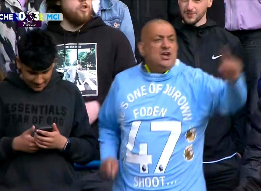 比赛中那一幕太扎心了。曼城多库打进一球后，一位身穿曼城球衣的粉丝突然举起阿森纳水