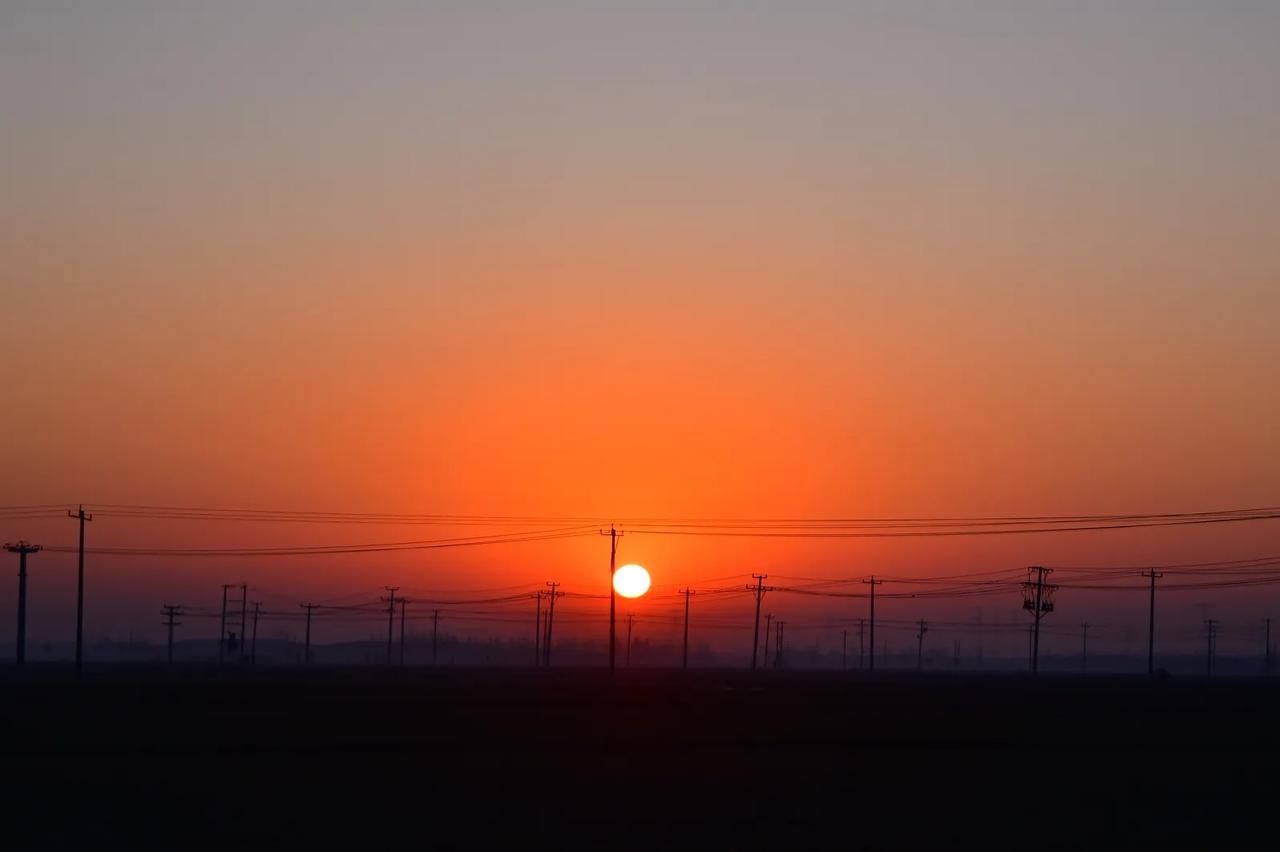 麦田日出，你看在辽阔无垠的麦田地里，红彤彤的太阳露头了，普照大地，朝霞满天。