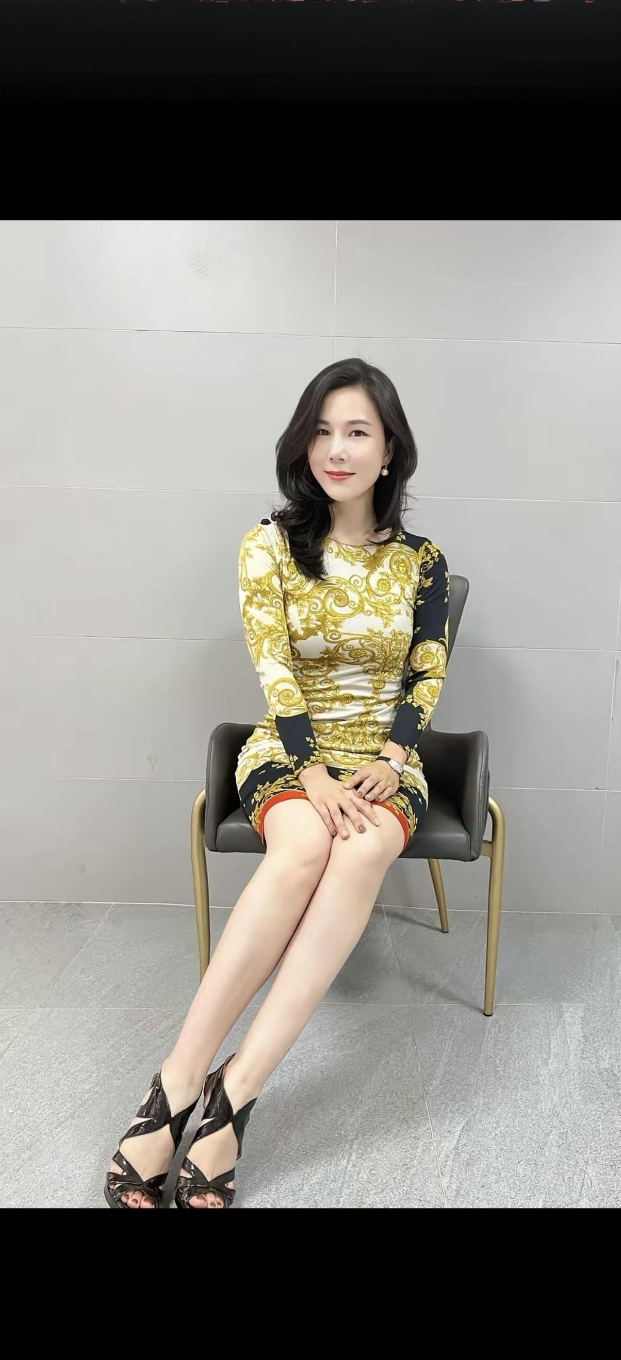这姑娘坐在椅子上，穿着漂亮裙子。
