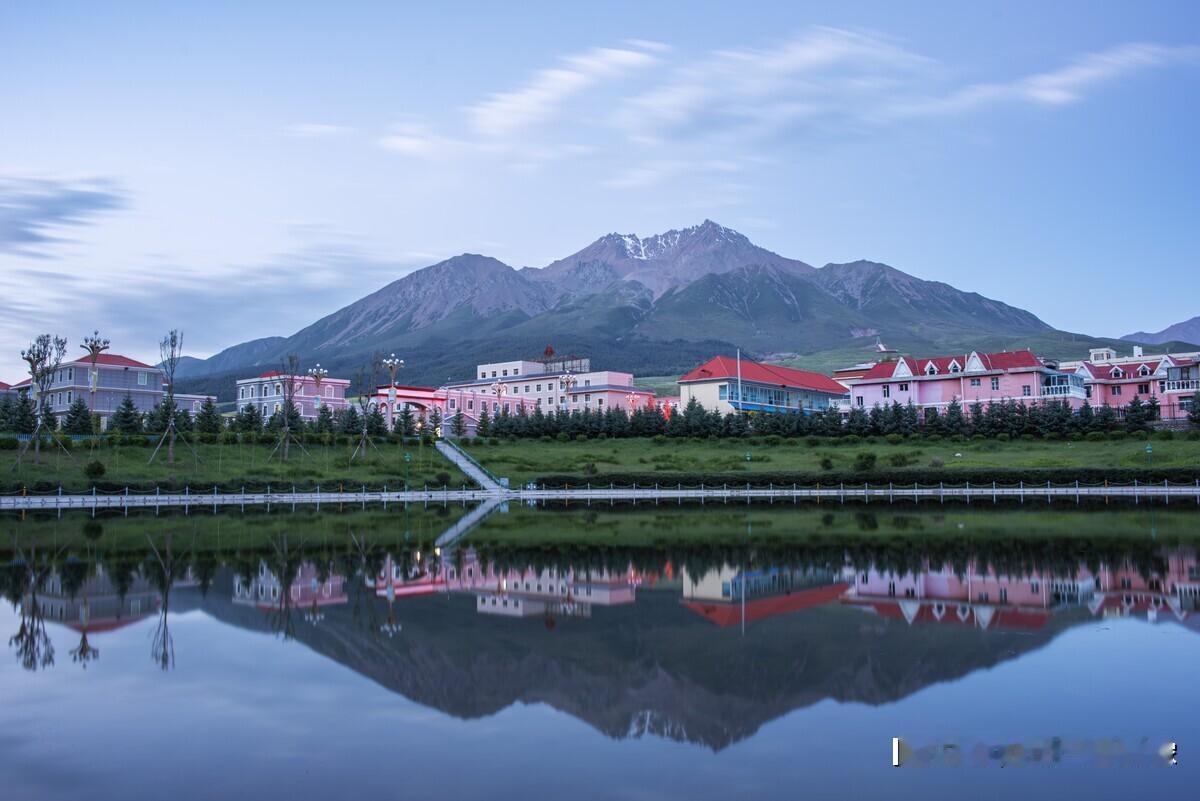 青海祁连县有着“东方小瑞士”的美称，清晨的小县城，一方池塘水面如镜倒映着远处的雪