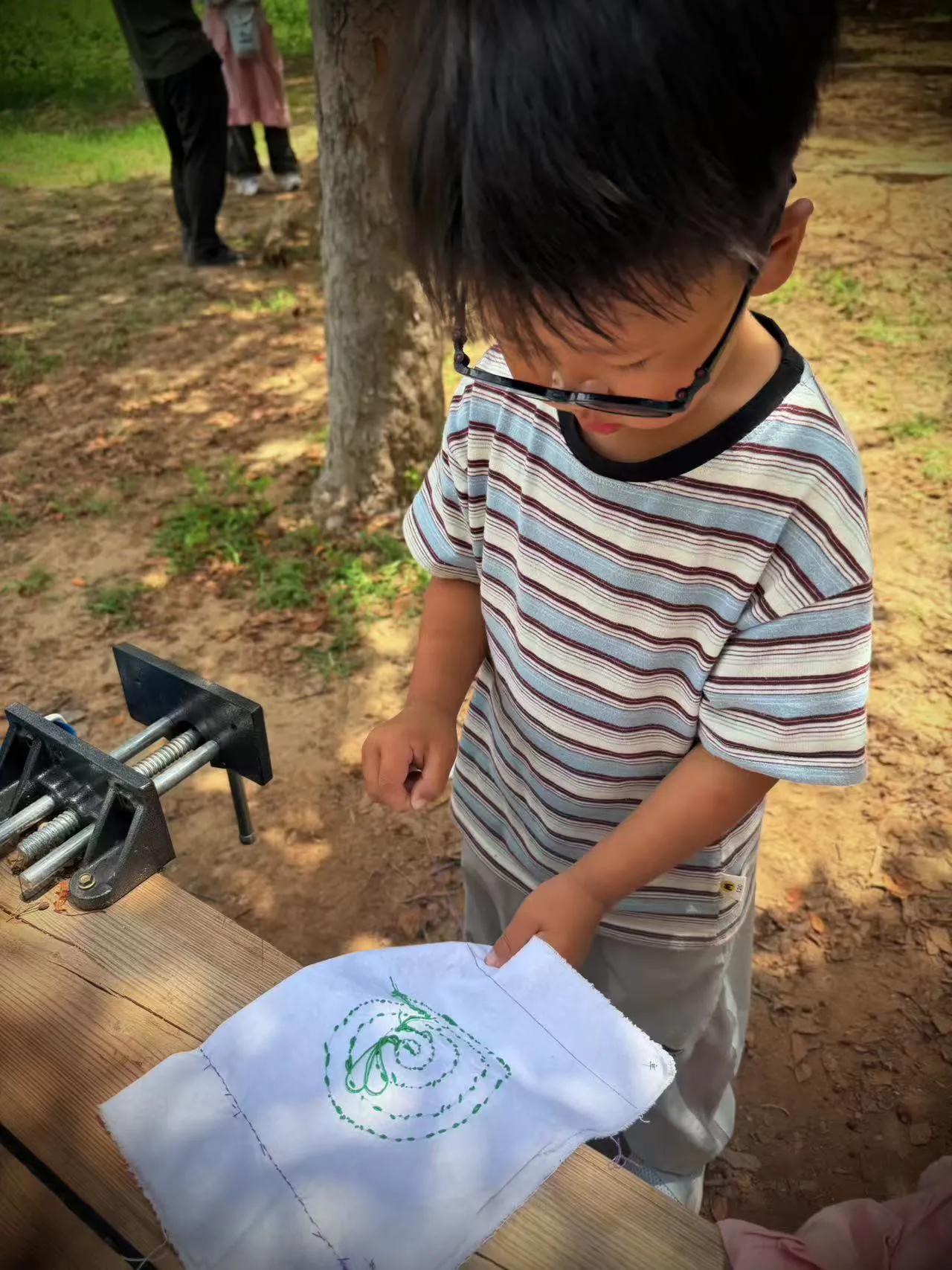 幼儿园里，孩子们拿起小巧绣针，笨拙又认真地学刺绣。彩线在布面穿梭，小手慢慢勾勒小