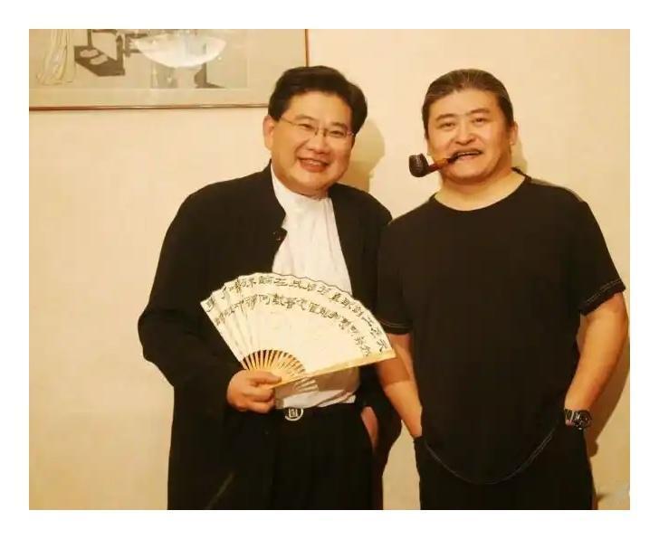 右边嘴里叼着烟斗双手插兜的是刘欢，一脸神气的样子酷毙了，左边这位单手插兜，扇着折