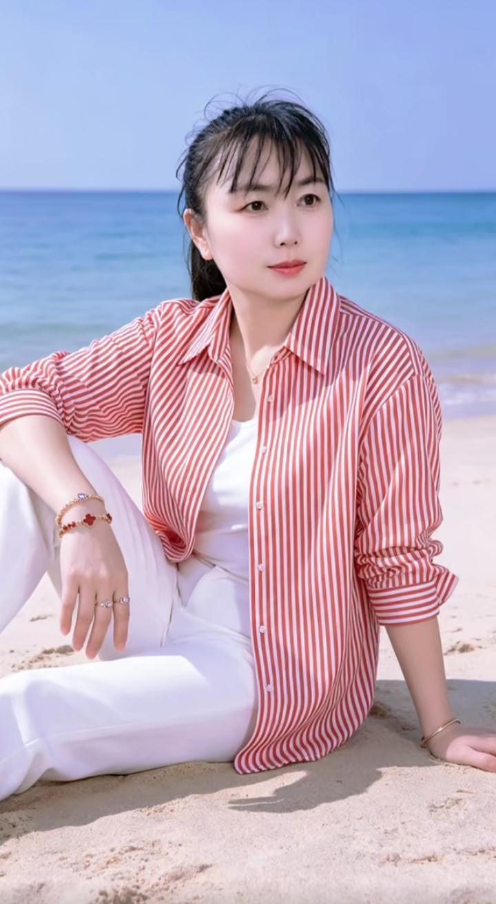 沙滩上，穿着条纹衬衫，阳光明媚。女人打扮那么漂亮是给谁看 休闲文艺衬衫女 海边白