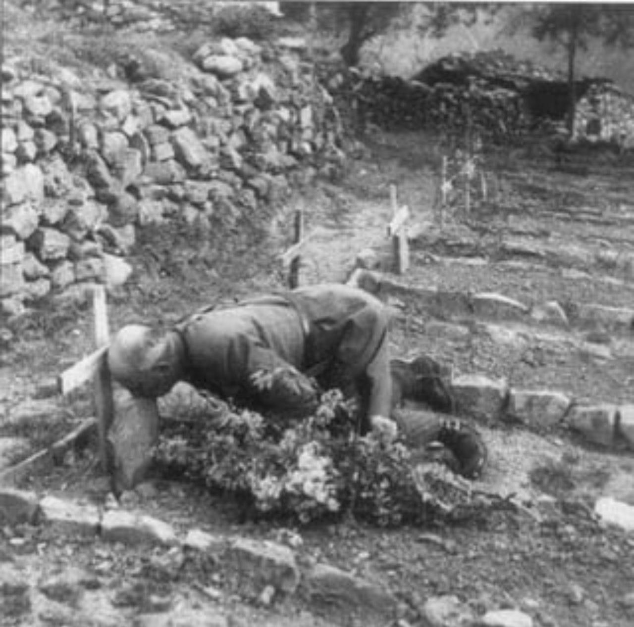 黑白照片显示，1941 年，在阿尔巴尼亚前线一座石墙环绕的野战公墓里，一位秃顶的