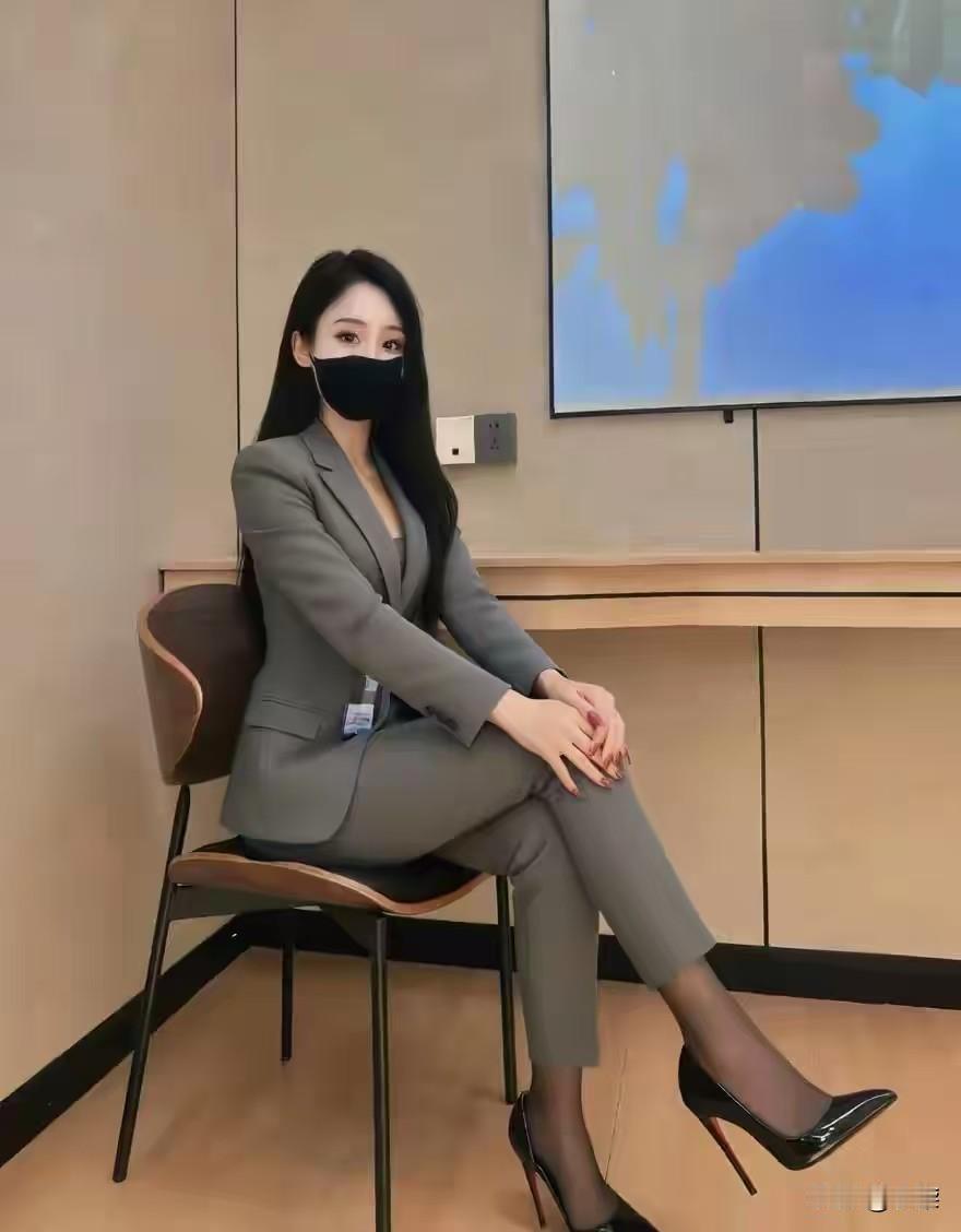 浅灰西装裁开清晨的风
椅上侧坐，是从容的弧度
黑高跟与黑丝，撞出克制的性感
方寸