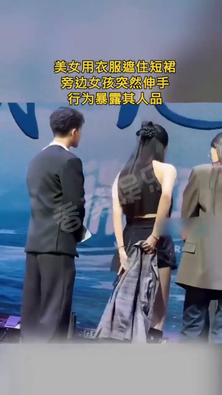 美女用衣服遮住短裙，旁边女孩突然伸手，行为暴露其人品。