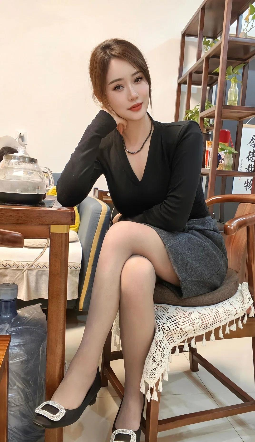 小姨子坐在茶桌前，优雅黑裙，精致妆容，