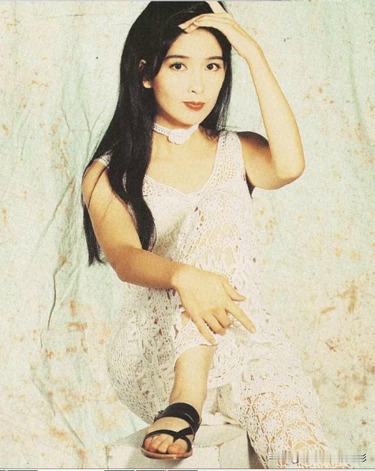 周慧敏年轻时的经典写真，一身镂空白裙，长发披肩，气质清纯又带着点慵懒的性感。她的