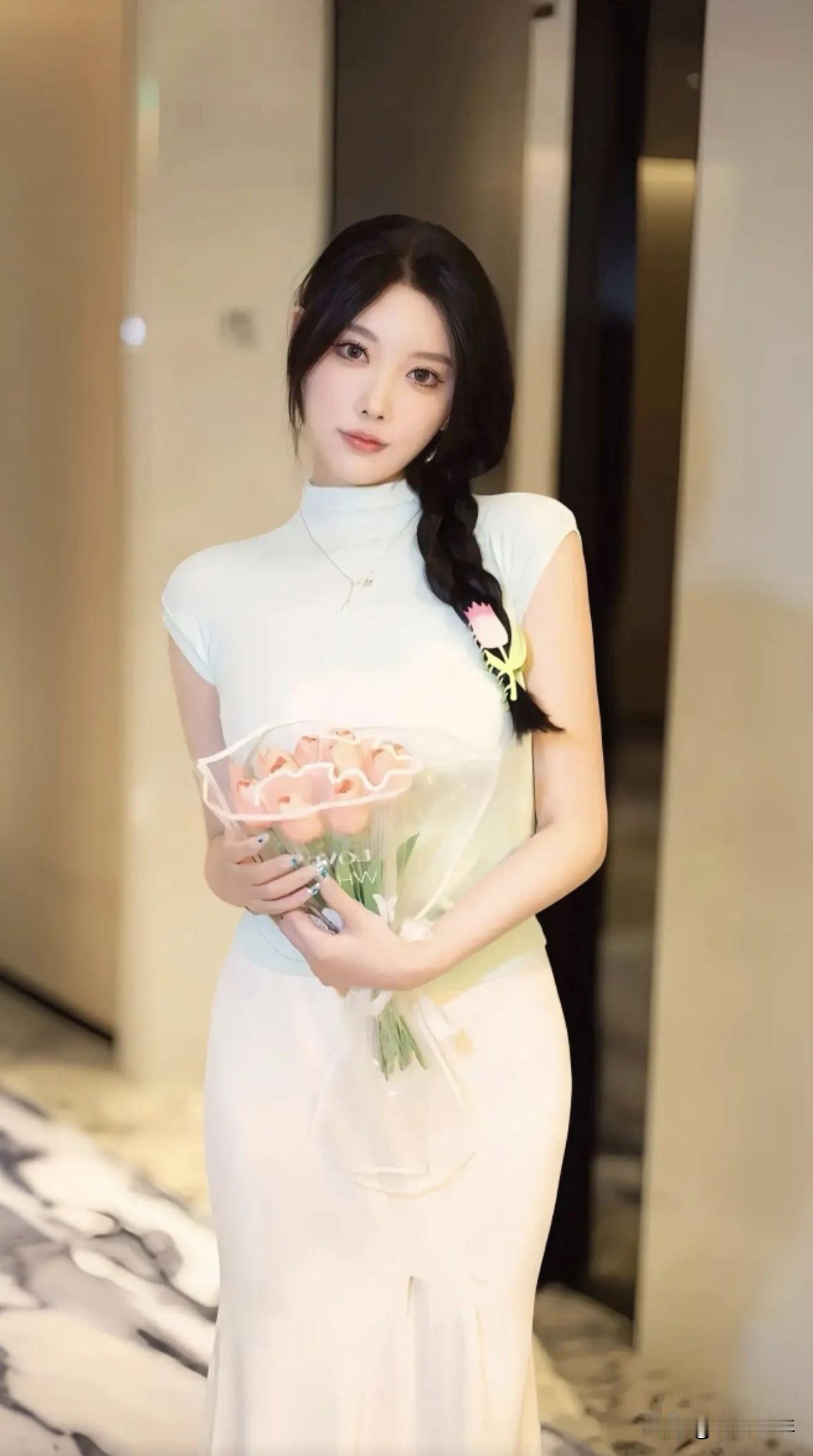 一个漂亮姑娘拿着花站在走廊里。