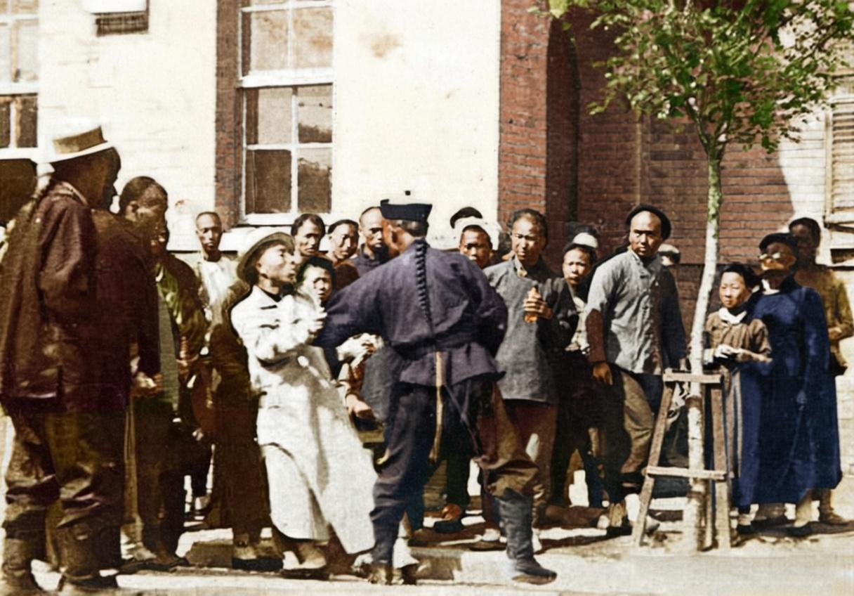 这张照片拍摄于清末民初的山东街头，一名身着新式警服的官差正用力拉扯着一位身穿长衫