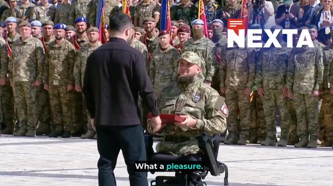 颁奖台上，泽连斯基弯腰为一名坐在轮椅上的士兵戴上英雄勋章。全场肃穆，只有快门声此