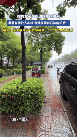 太治愈了！暴雨突然来袭，摆摊女子一时无处避雨，只能打着伞缩在摊位旁，那无助的样子