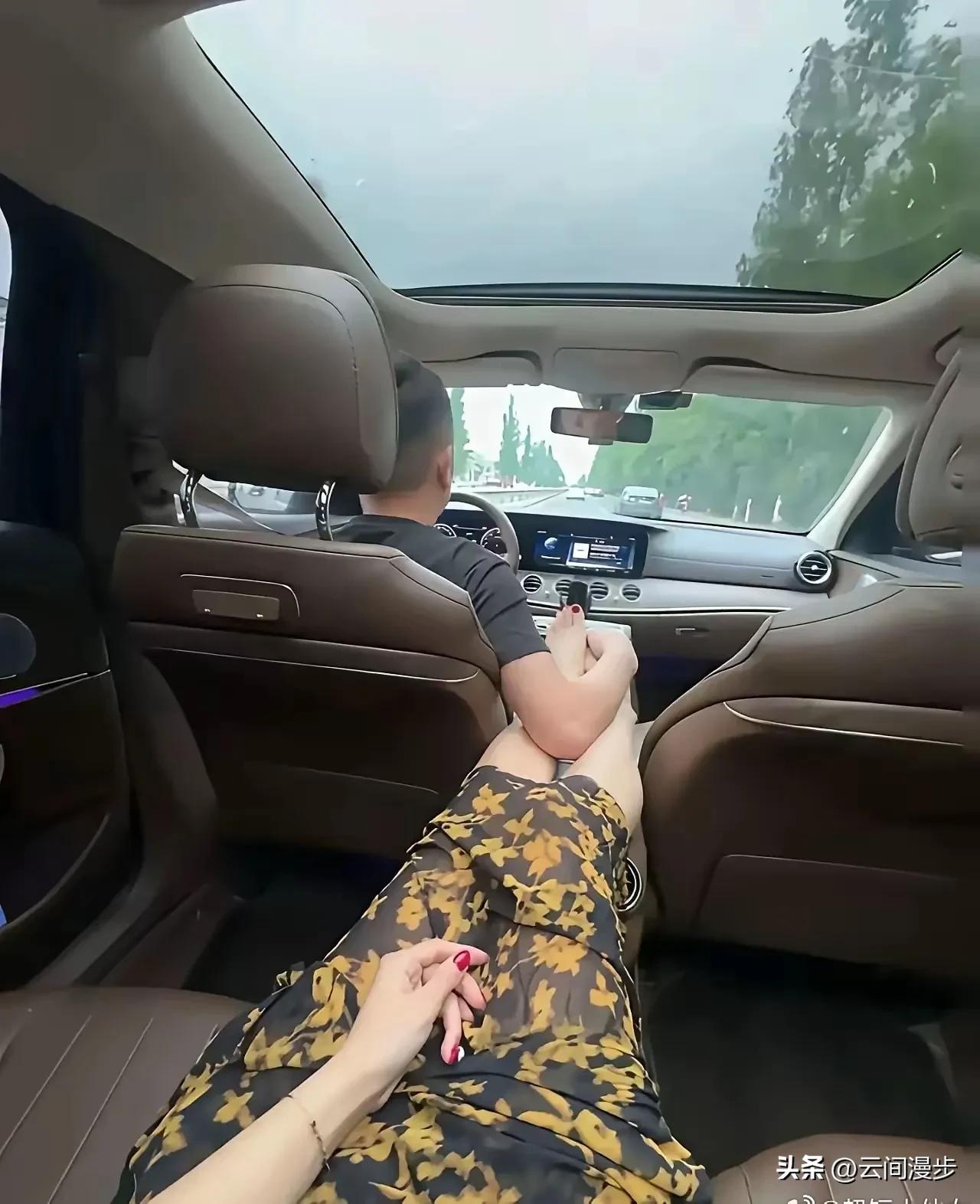 家人们谁懂啊！男人正开车行驶在路上，后座女孩伸出腿，司机居然一手握着方向盘，一手