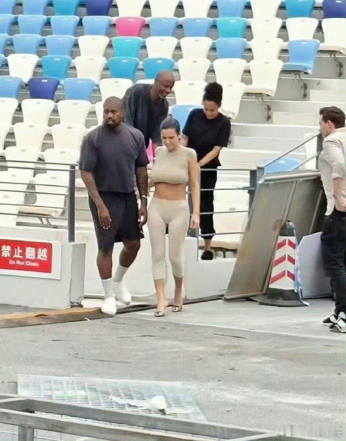#侃爷带妻子翻越栏杆# 侃爷妻子穿搭从未输过，虽旁边警示牌写着“禁止翻越”，依旧