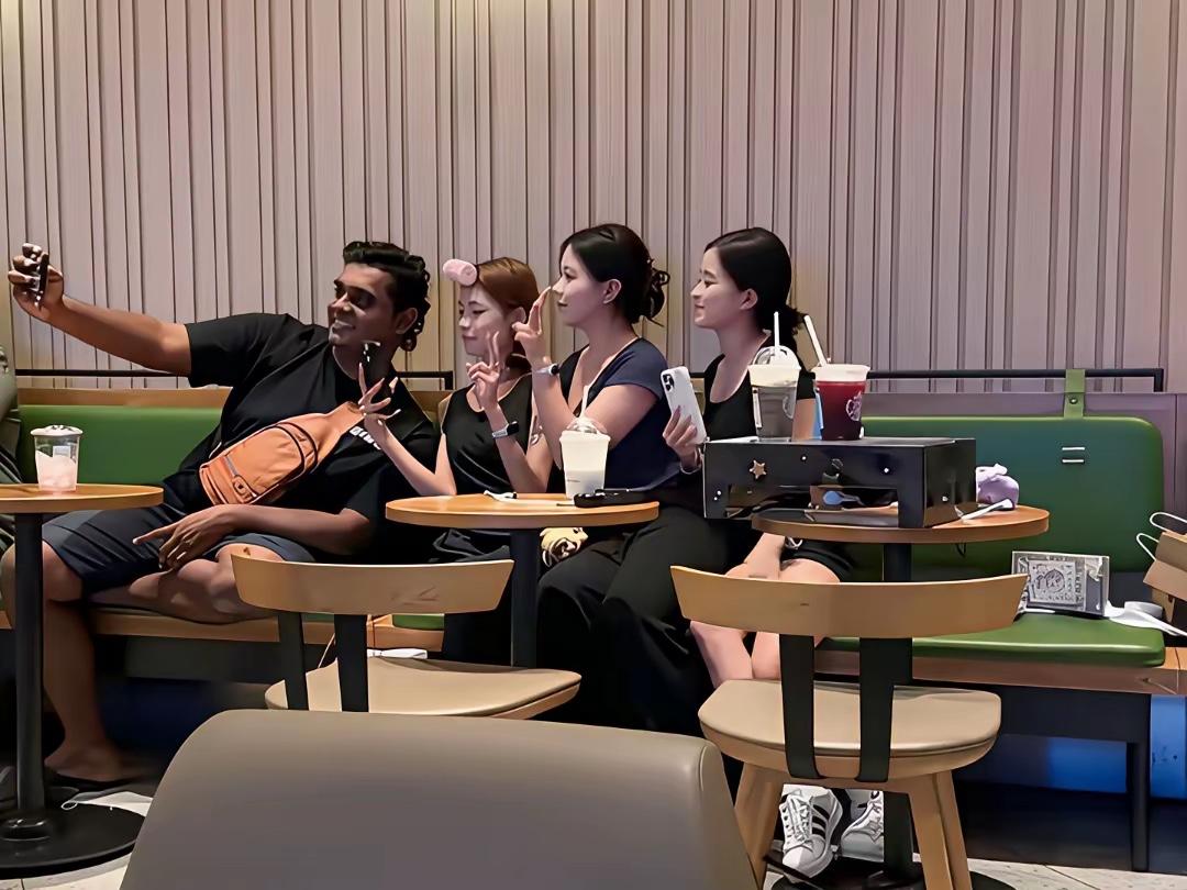 印度人主动和邻桌三个女孩合影，女孩们爽快的答应且配合。这不禁让人觉得，是不是大家