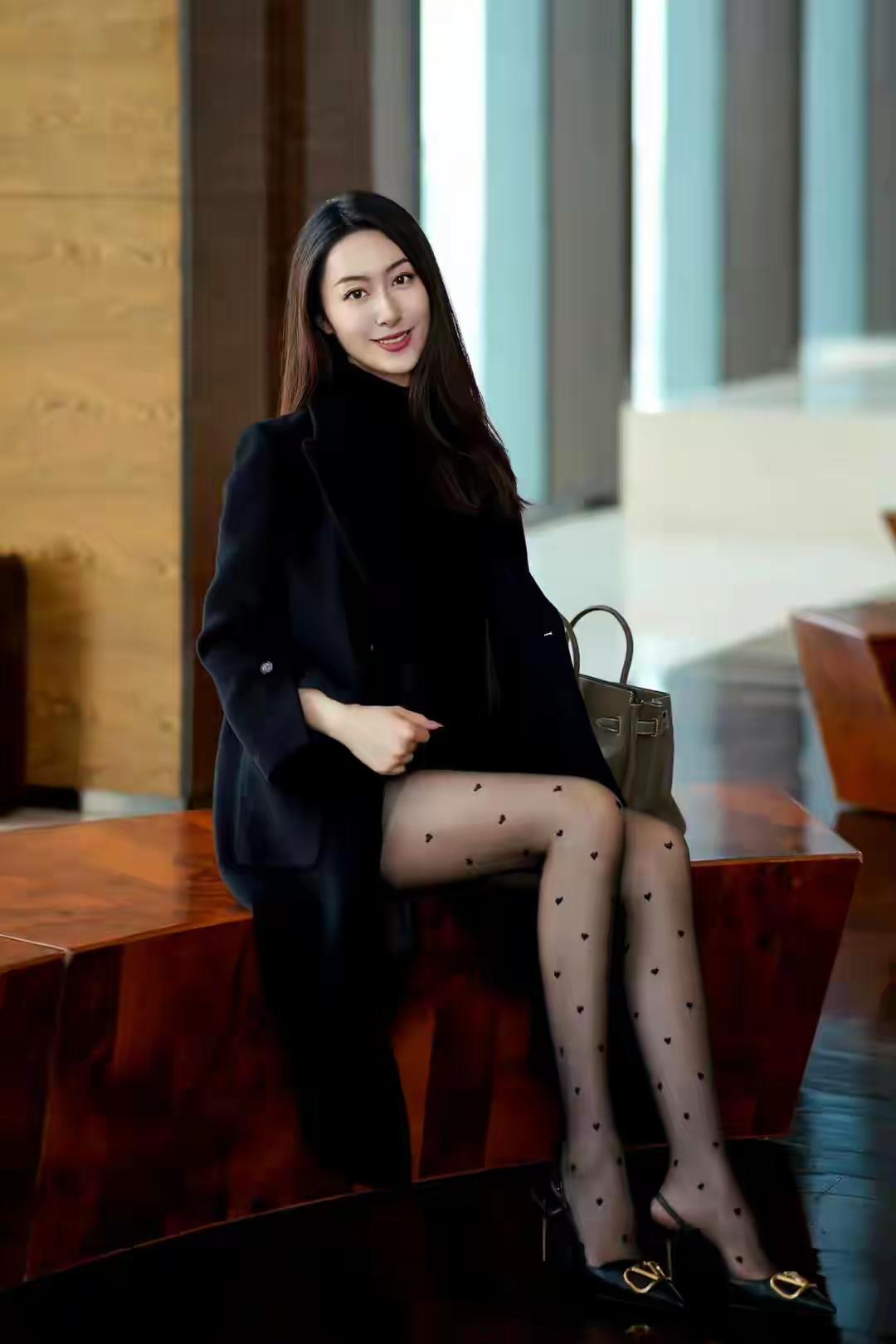 时髦精穿搭秘籍内穿黑色高领打底衫搭配黑色的短裙，外搭一件质感十足的大衣，一双波点